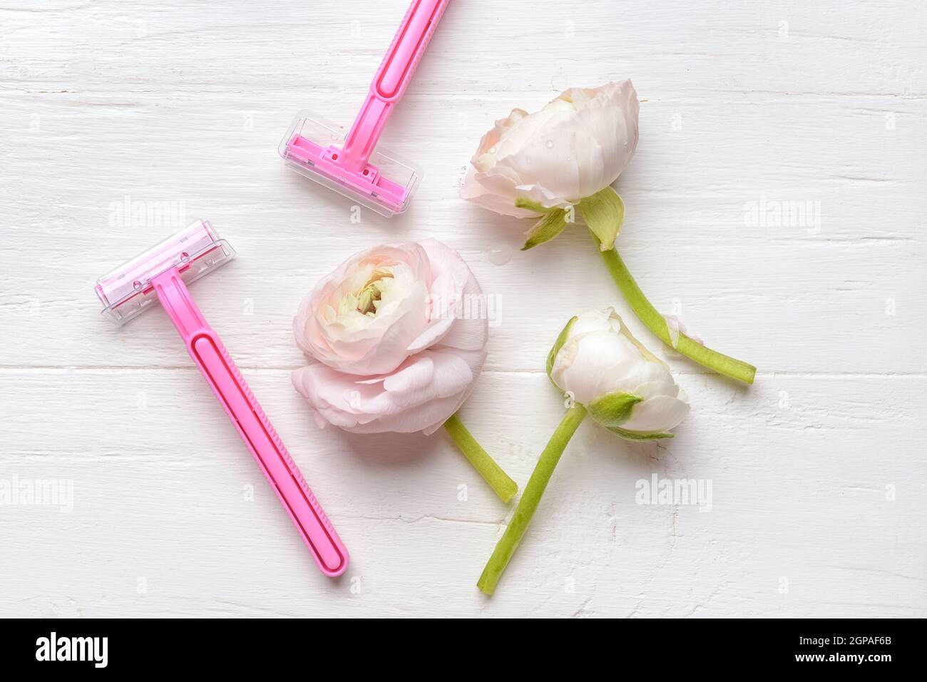 Safety razors and flowers on light wooden background Stock Photo - Alamy