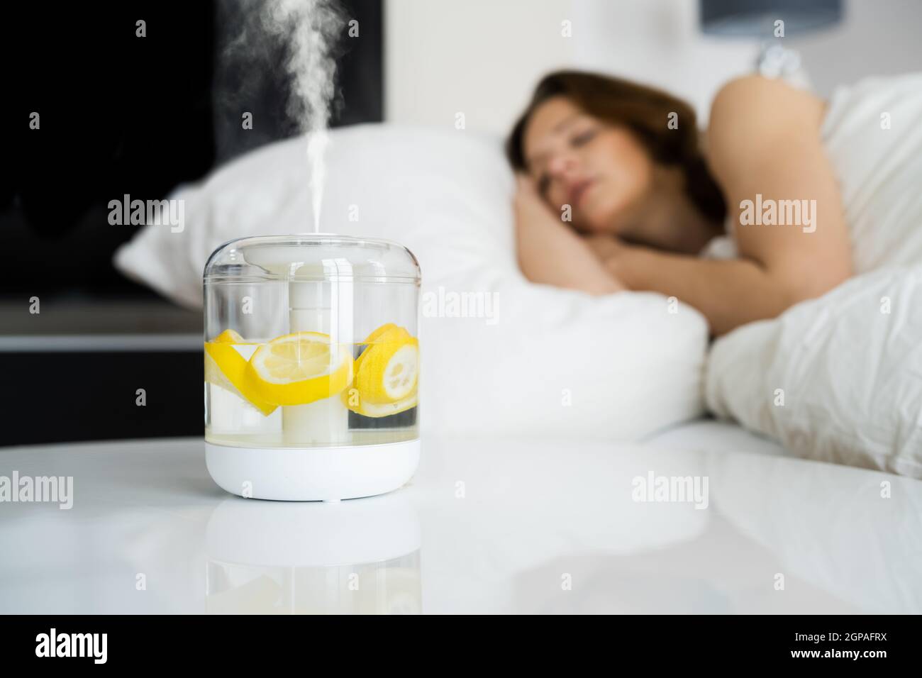 Home Air Humidifier Device In Bedroom Near Woman Sleeping Stock Photo