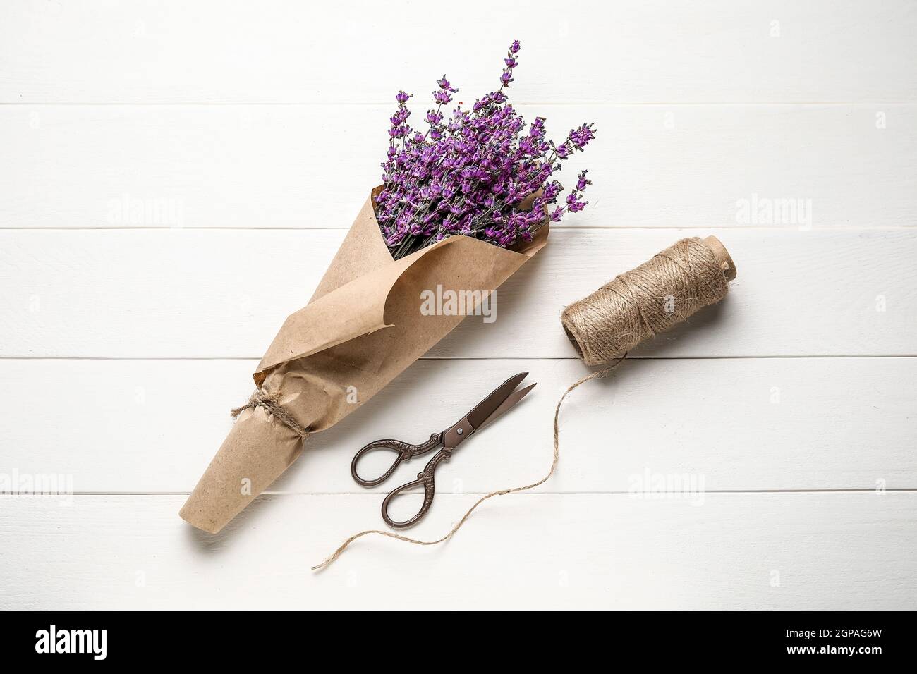 Bouquet of lavender flowers, scissors and rope on light wooden ...