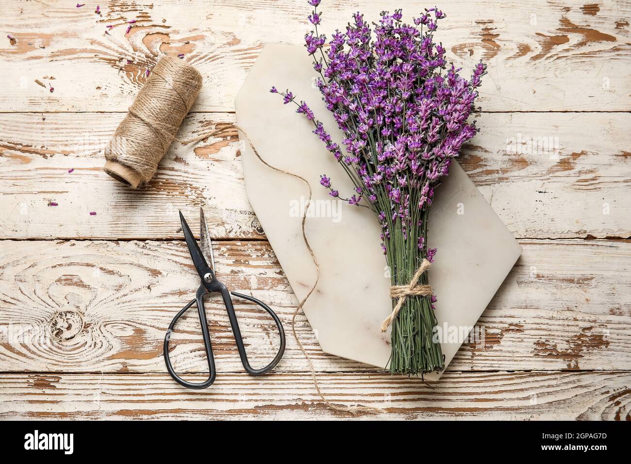 Bouquet of lavender flowers, scissors and rope on light wooden ...