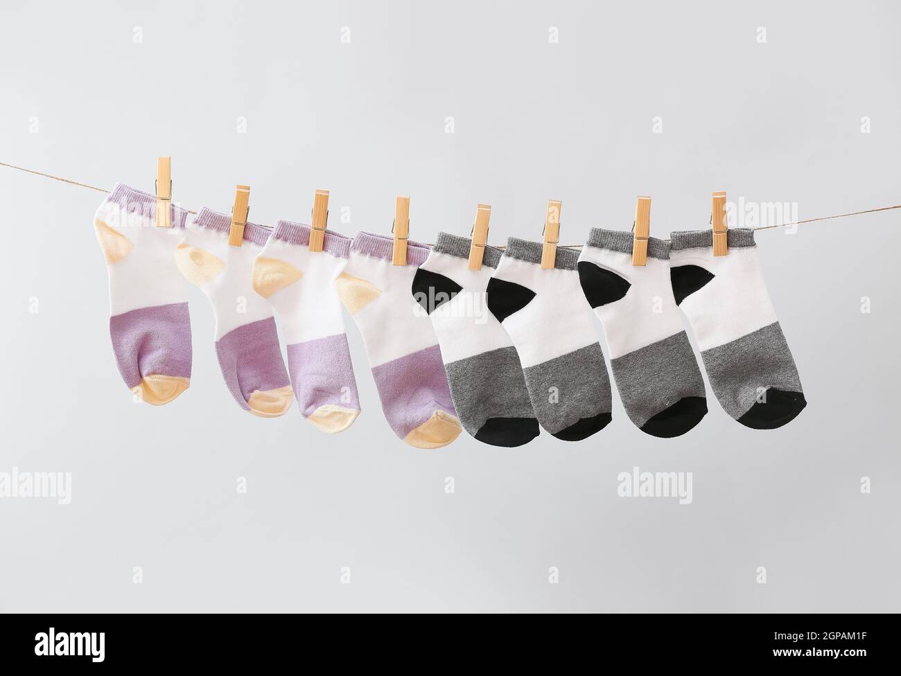 Different socks hanging on rope against grey background Stock Photo - Alamy