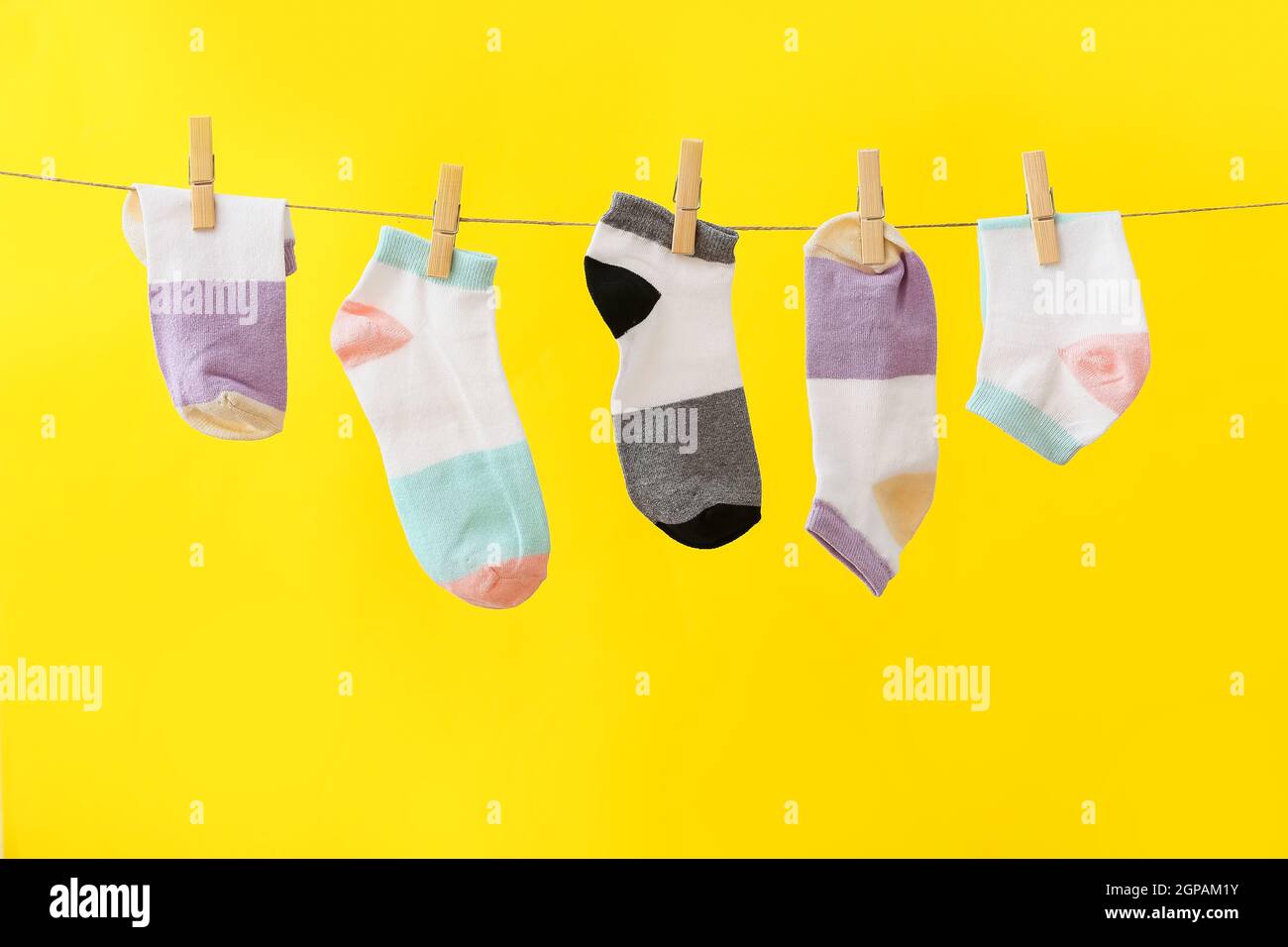 Different socks hanging on rope against yellow background Stock Photo ...