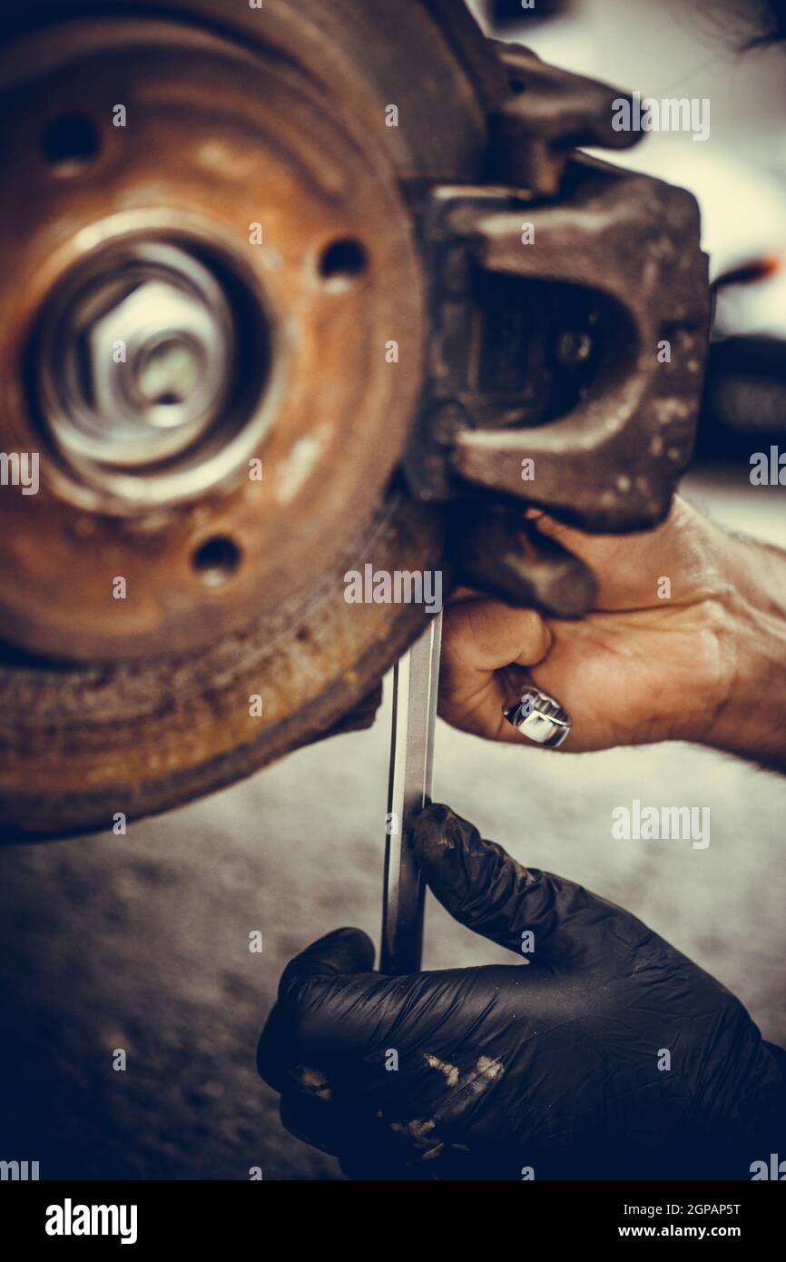Close up shot of a mechanic working at a car worn and rusty brake disk