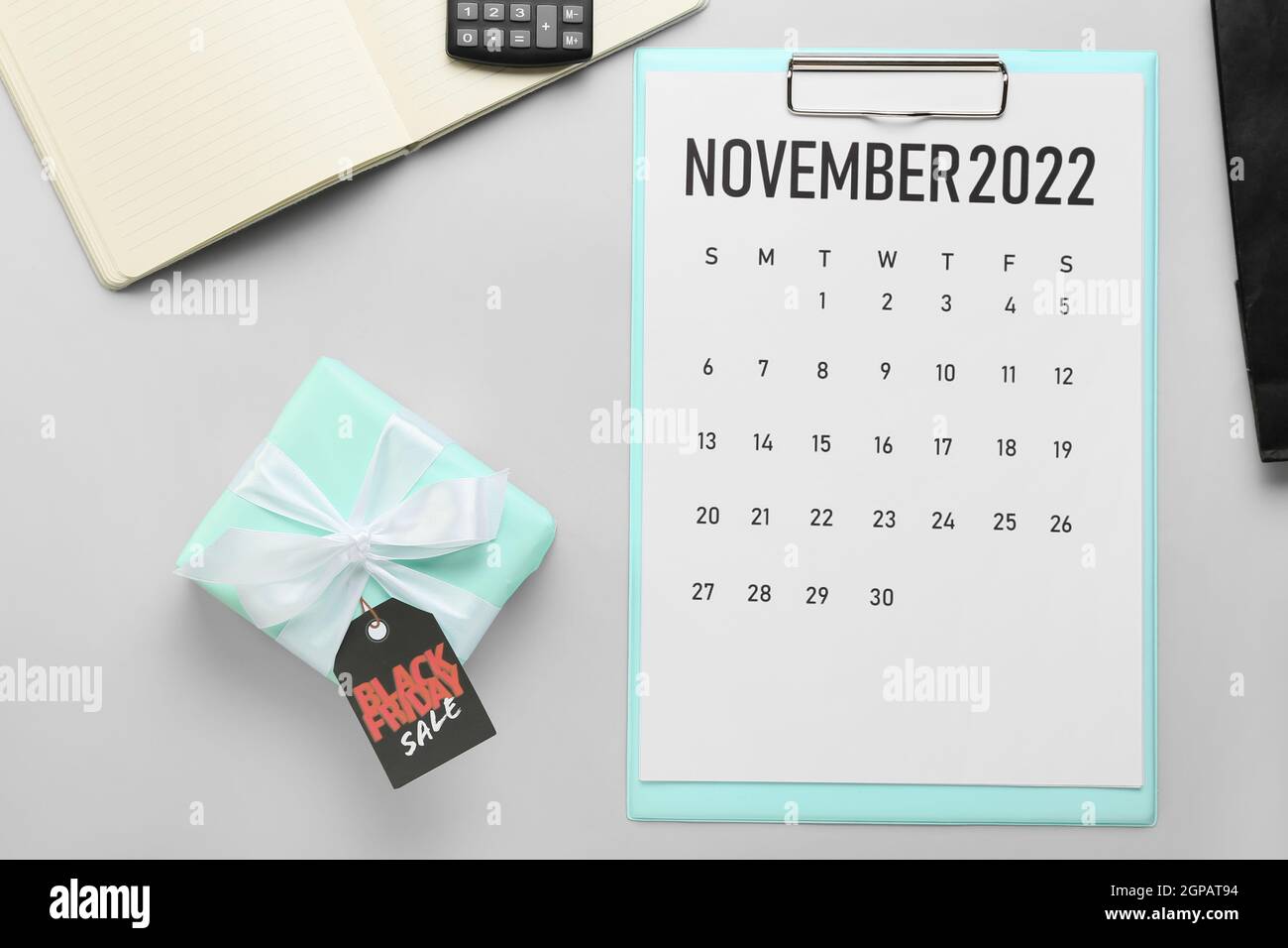 Calendar page of November 2022 and gift on grey background. Black