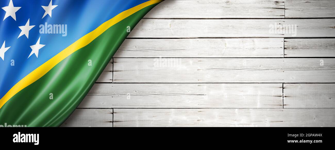 Solomon Islands flag on old white wall. Horizontal panoramic banner. Stock Photo