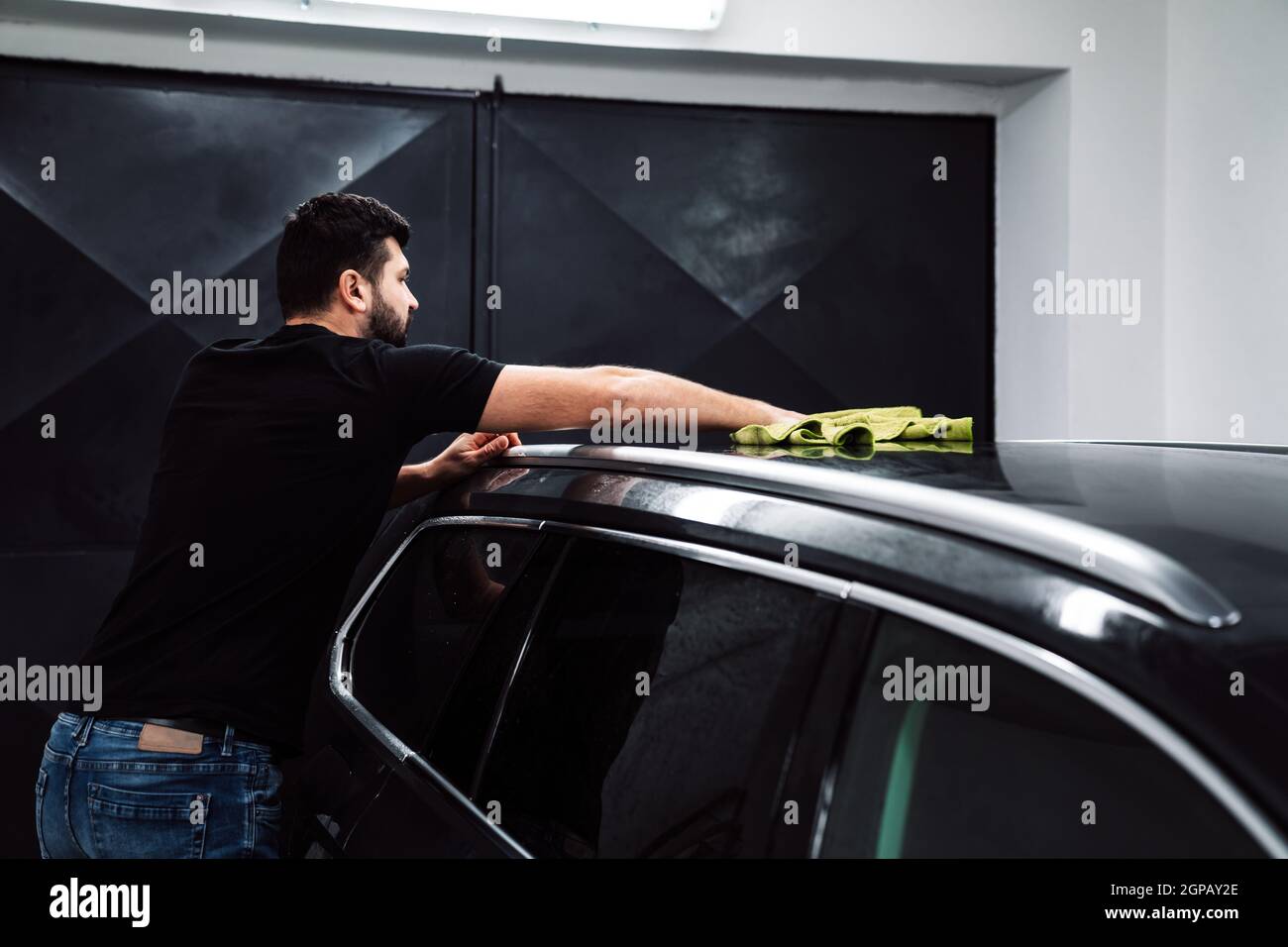 man cleans the car body with a towel. auto care. Stock Photo