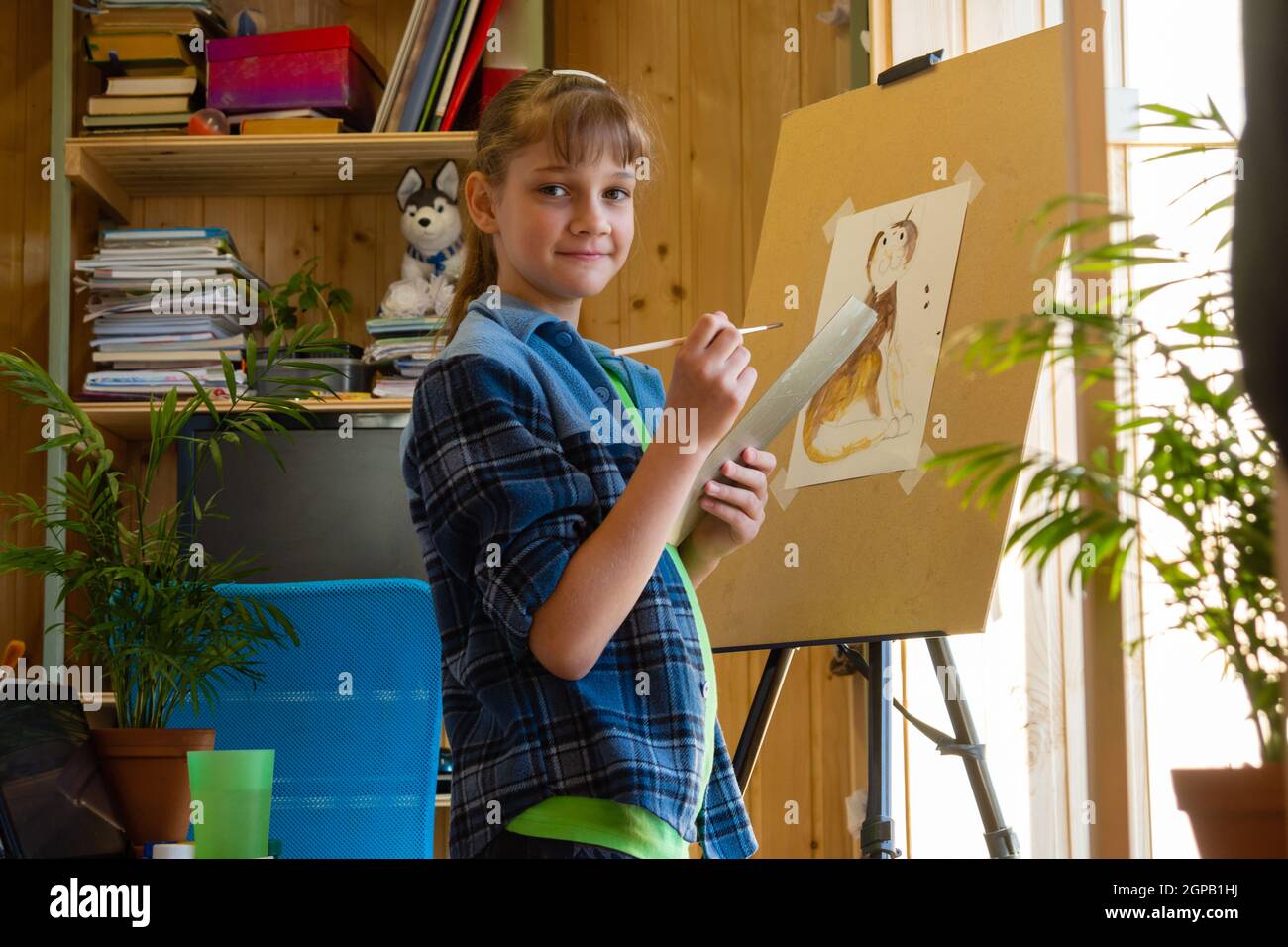 The girl was distracted from drawing on the easel and looked into the frame Stock Photo
