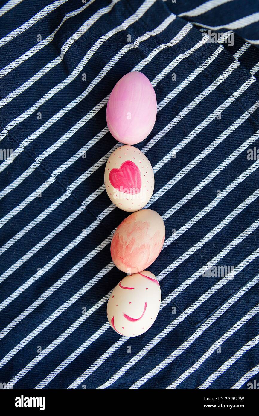 Beautiful Easter eggs painted with watercolors lie on a striped blue fabric. Easter holiday concept Stock Photo