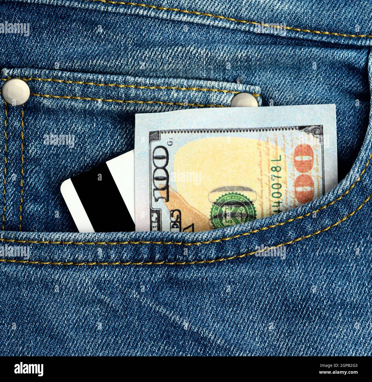 paper american dollars and plastic bank card with magnetic stripe in the pocket of blue jeans, close up Stock Photo