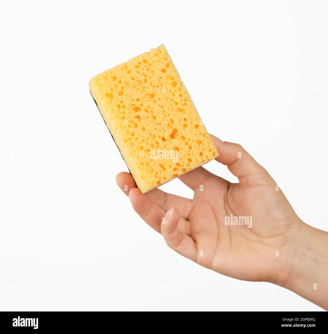 female hand holds a yellow kitchen sponge for washing dishes, part of the body on a white