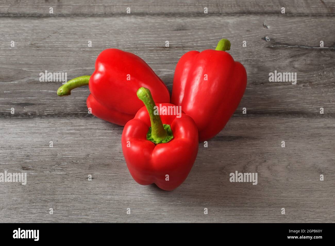 Table top view on three red bell peppers on a gray wood desk Stock ...