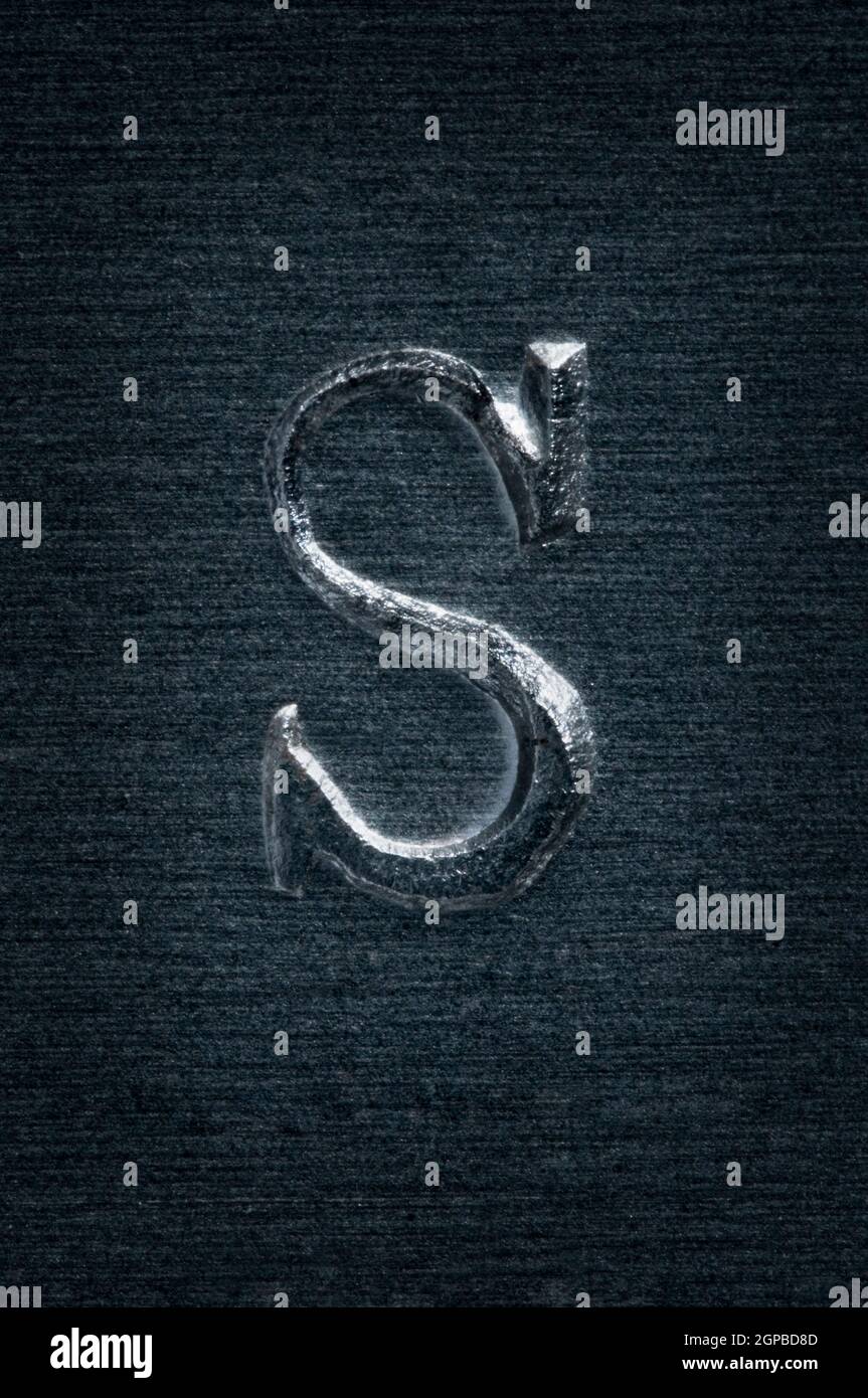 Detail view of the letter S embossed into a gray and sanded steel plate. Stock Photo