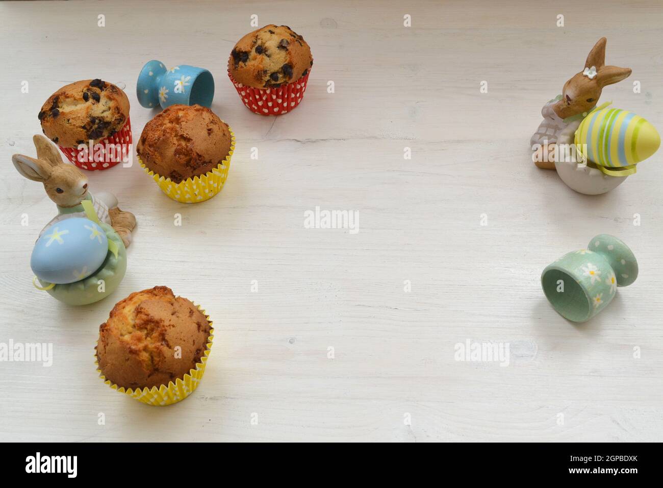 Easter table with muffins, colored eggs and bunnies. Copy space, white table Stock Photo