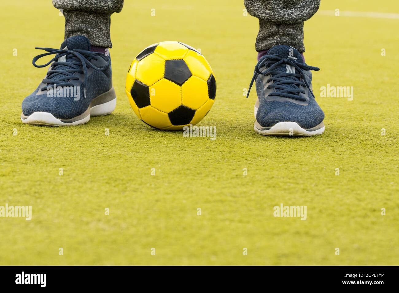 Feet of player with ball on artificial turf soccer field Stock Photo