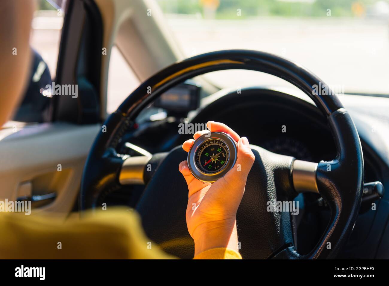 Asian woman inside a car and using compass to navigate while driving