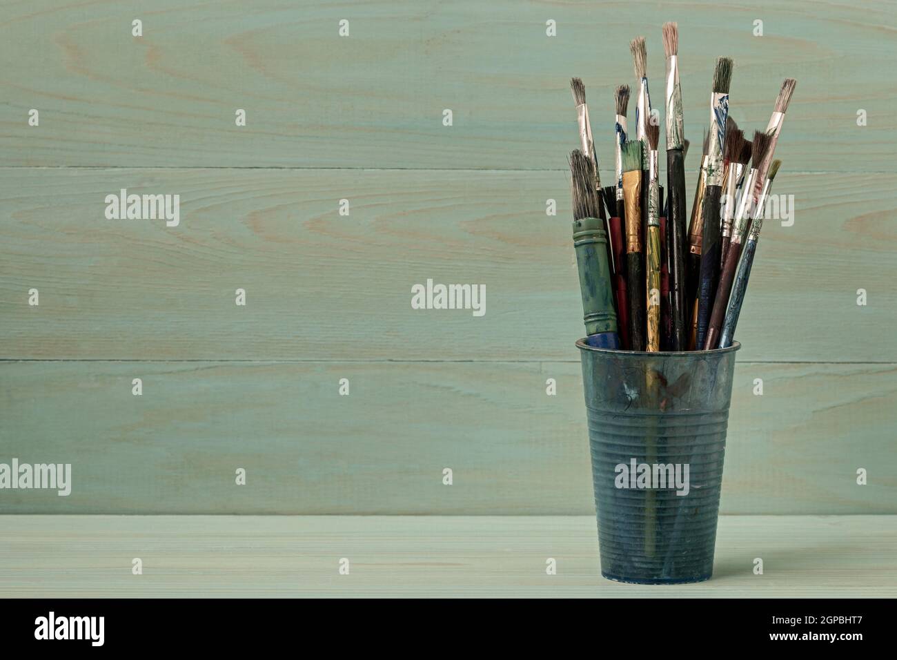 Assorted dirty painting brushes in plastic flask Stock Photo
