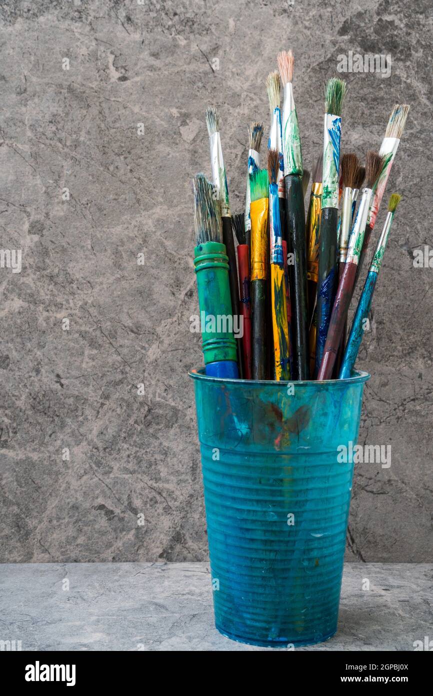 Dirty plastic flask with assorted painting brushes Stock Photo