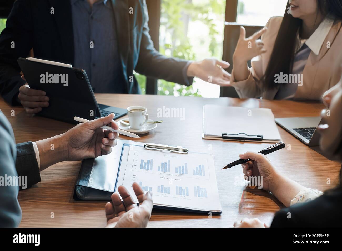Multiracial business people gather to discuss the company's market plan for the coming year. Teamwork Togetherness Unity Concept. Stock Photo