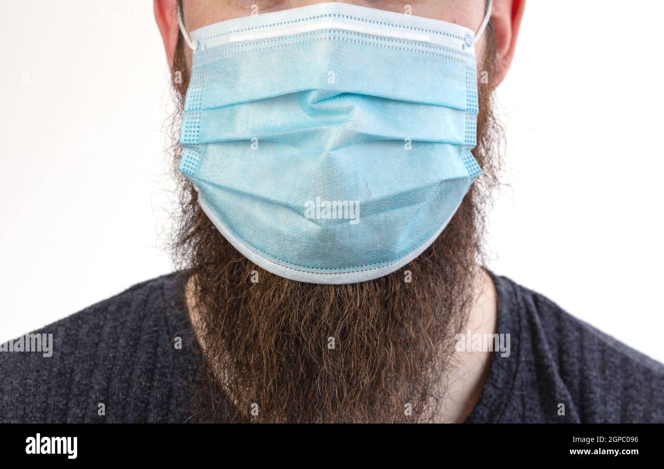 Caucasian young bearded adult man wearing a protective or surgical mask ...