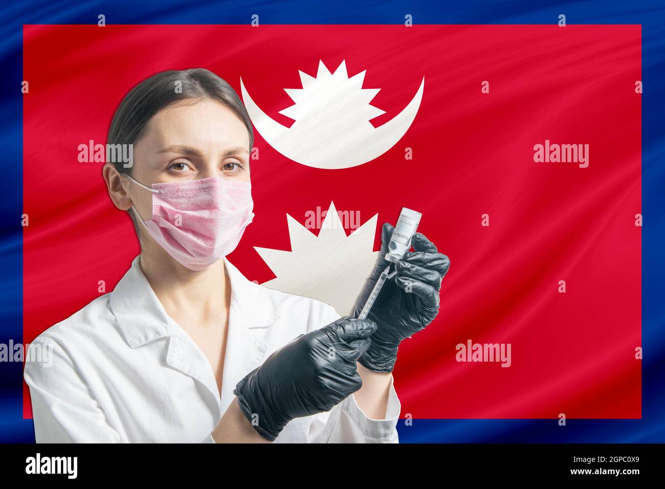 Girl doctor prepares vaccination against the background of the Nepal flag. Vaccination concept Nepal. Stock Photo