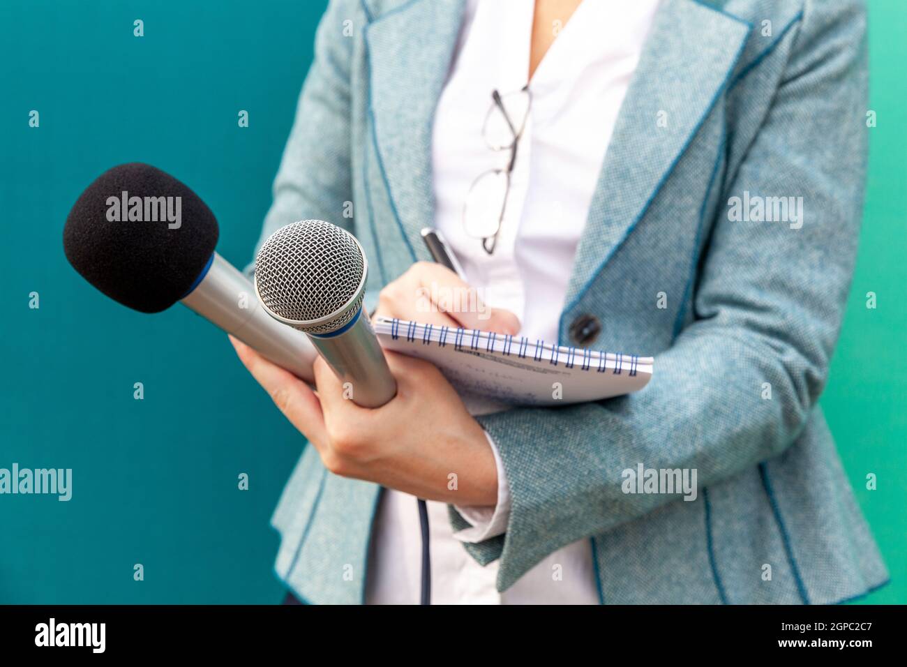 Female reporter at press conference, writing notes, holding microphone ...