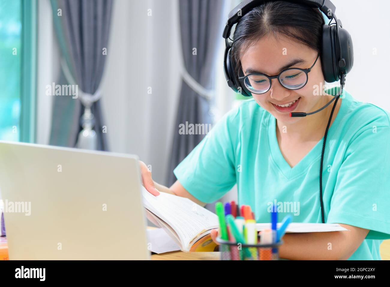 Portrait young Asian woman student with headphones glasses is smiling ...