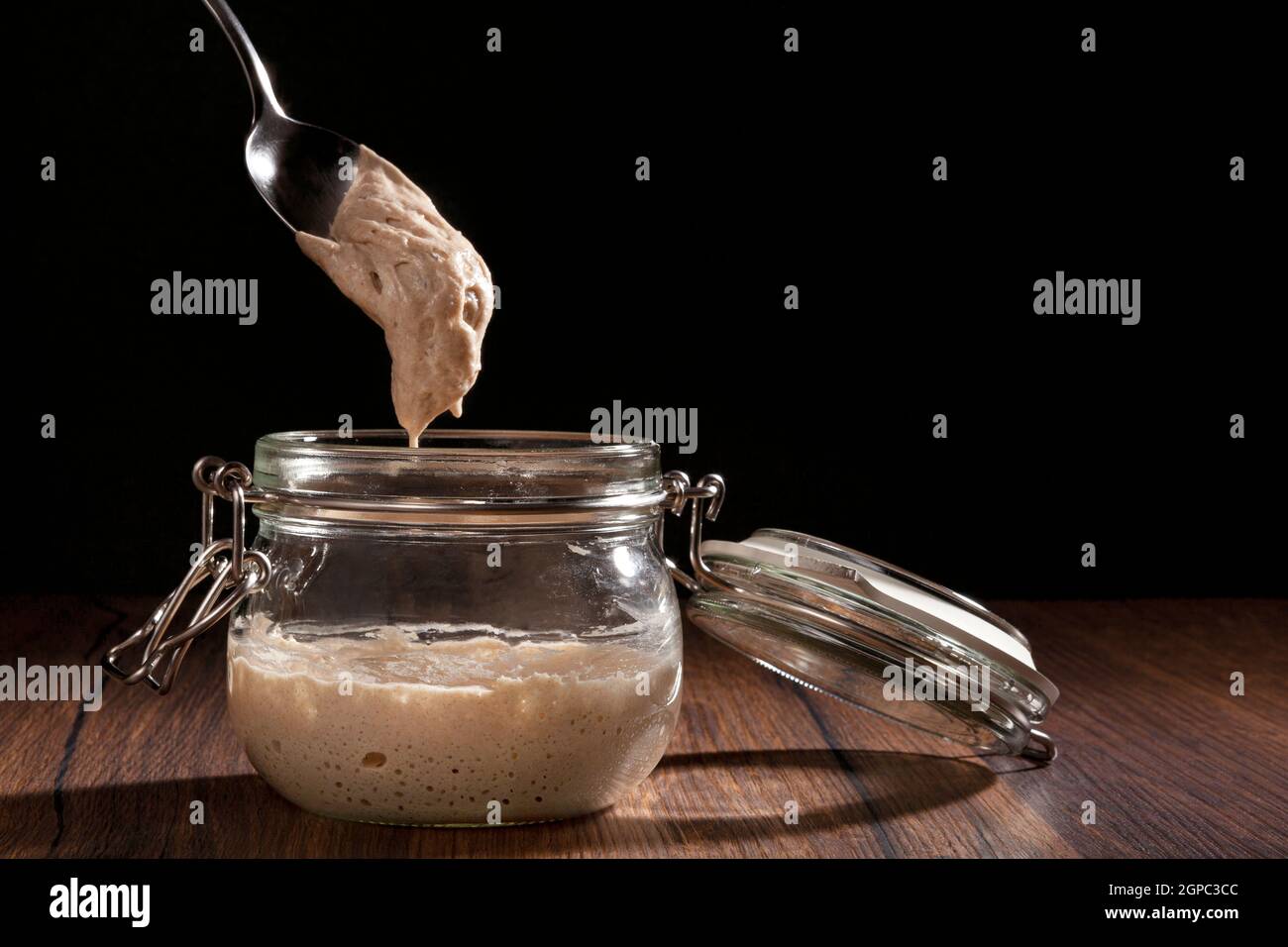 Sourdough starter in glass jar. Bread making background. Yeast. Stock Photo