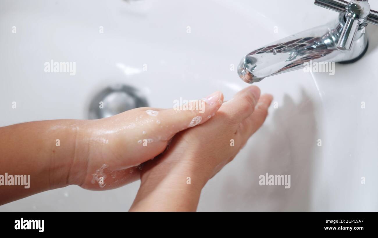 Closeup young woman hands using soap and washing hands under the water ...