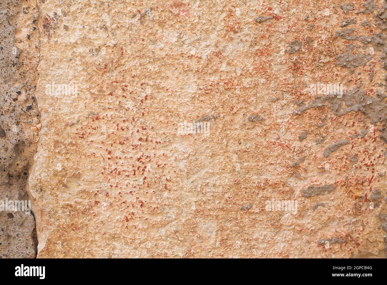 Beige and orange big stone block of wall with cement and red paint dots. Background and wallpaper textured picture. Copy space. Natural construction Stock Photo
