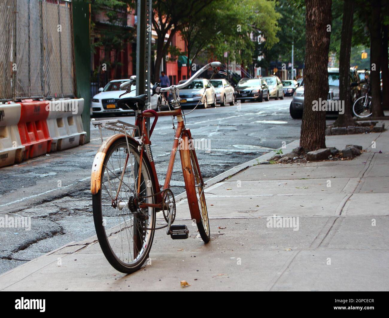 Single Worn Bike Locked and Parked Leaning on Pole Stock Photo