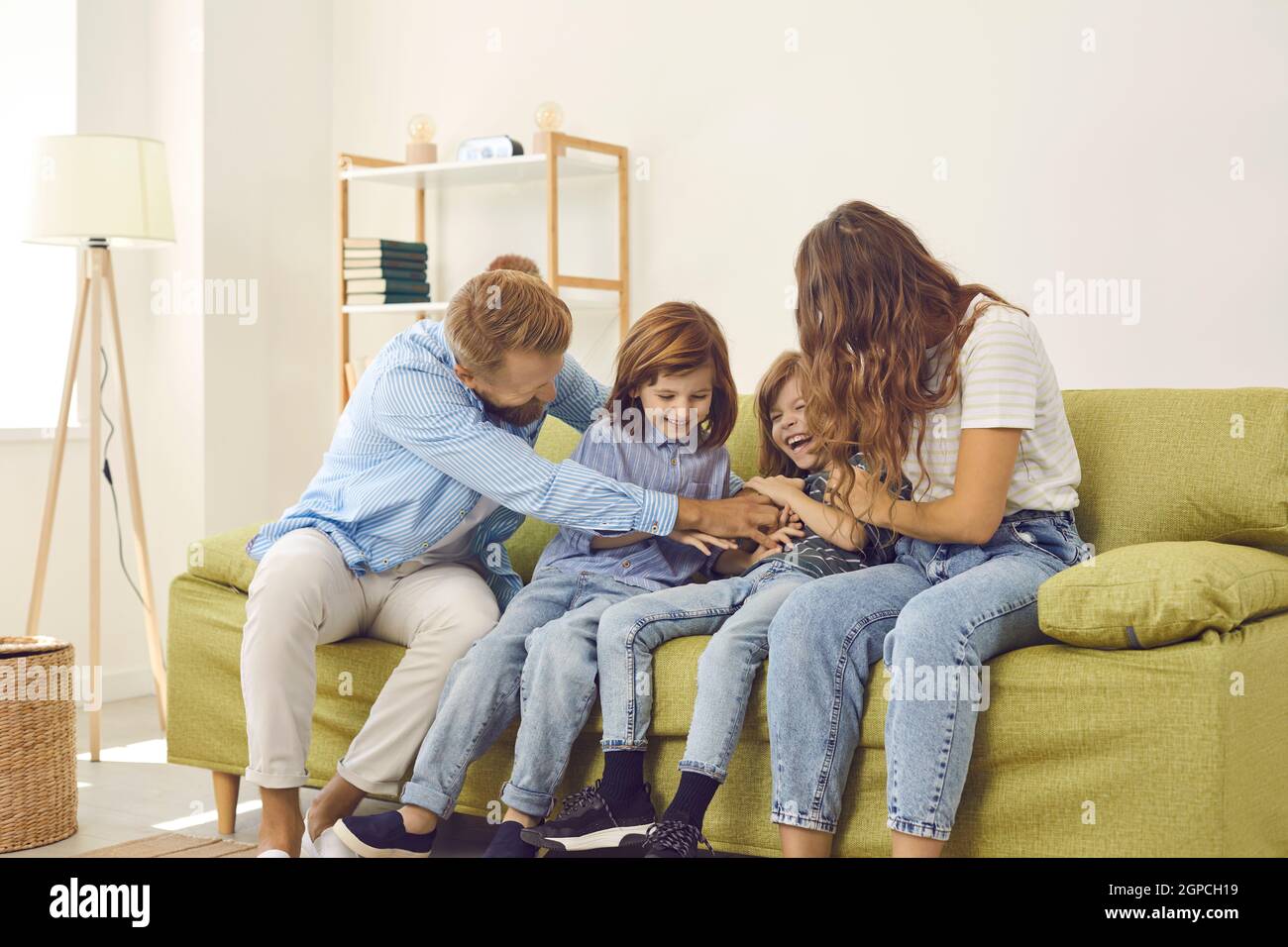 Young carefree couple is playing and having fun with their little twin sons at home. Stock Photo