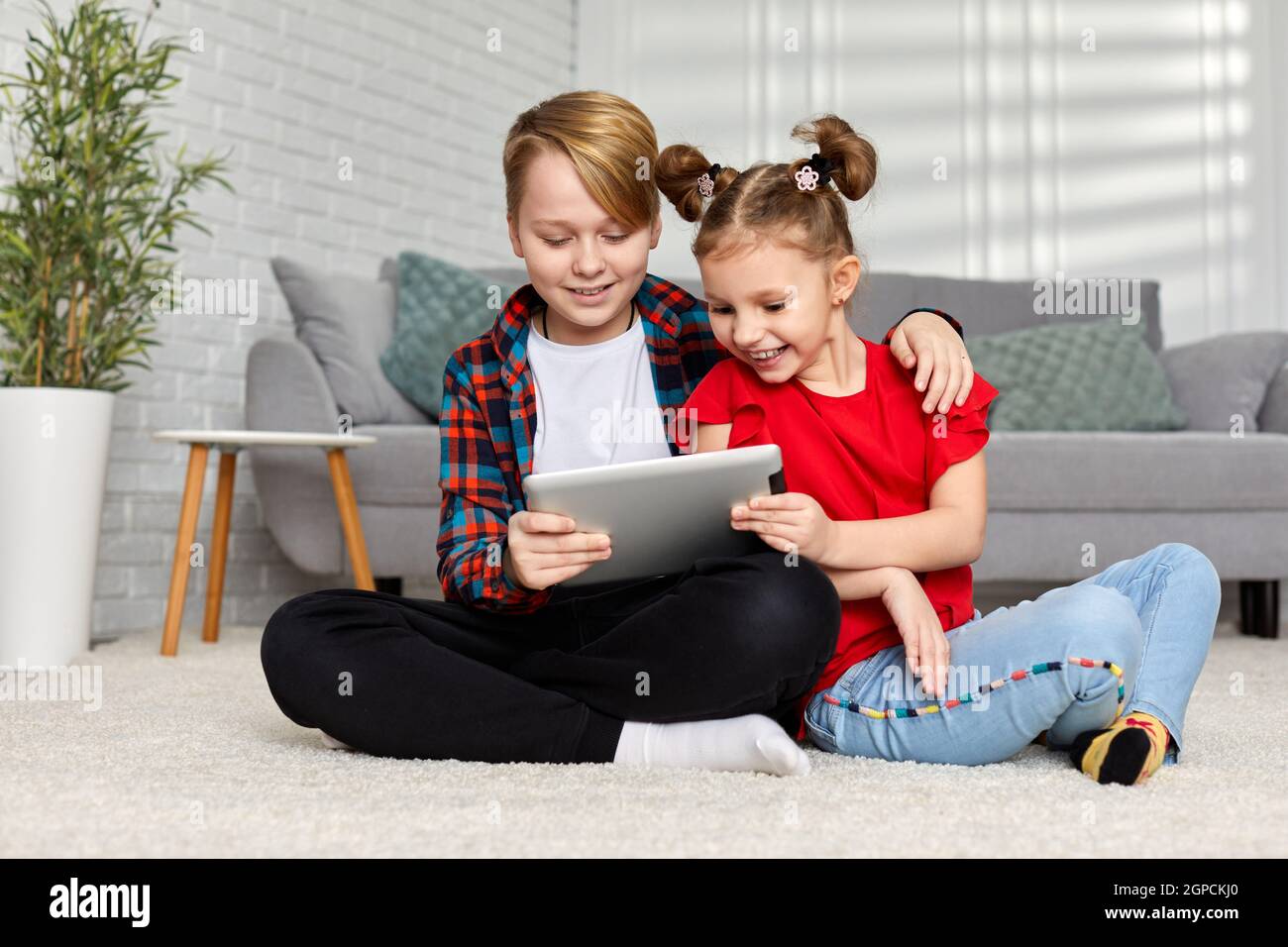 cute brother and sister use gadgets at home. Children play with a