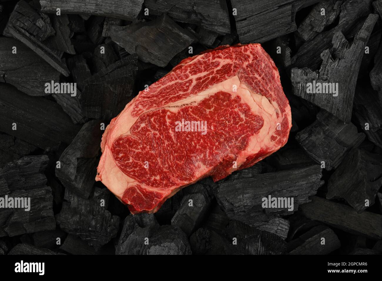 Beef Lump Close up one aged prime marbled raw ribeye beef steak on black lump ...