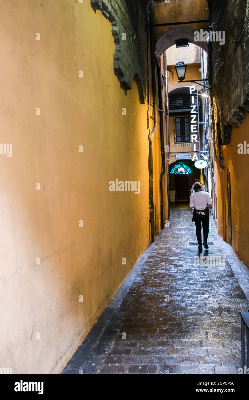 Person walking along narrow street to a pizzeria in Perugia Italy Stock Photo