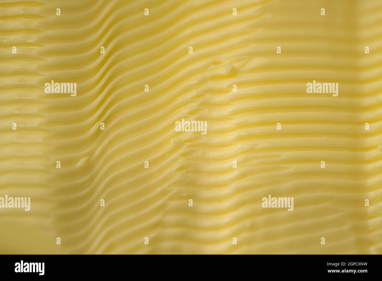 Full frame background texture of ripples in yellow margarine. Possible