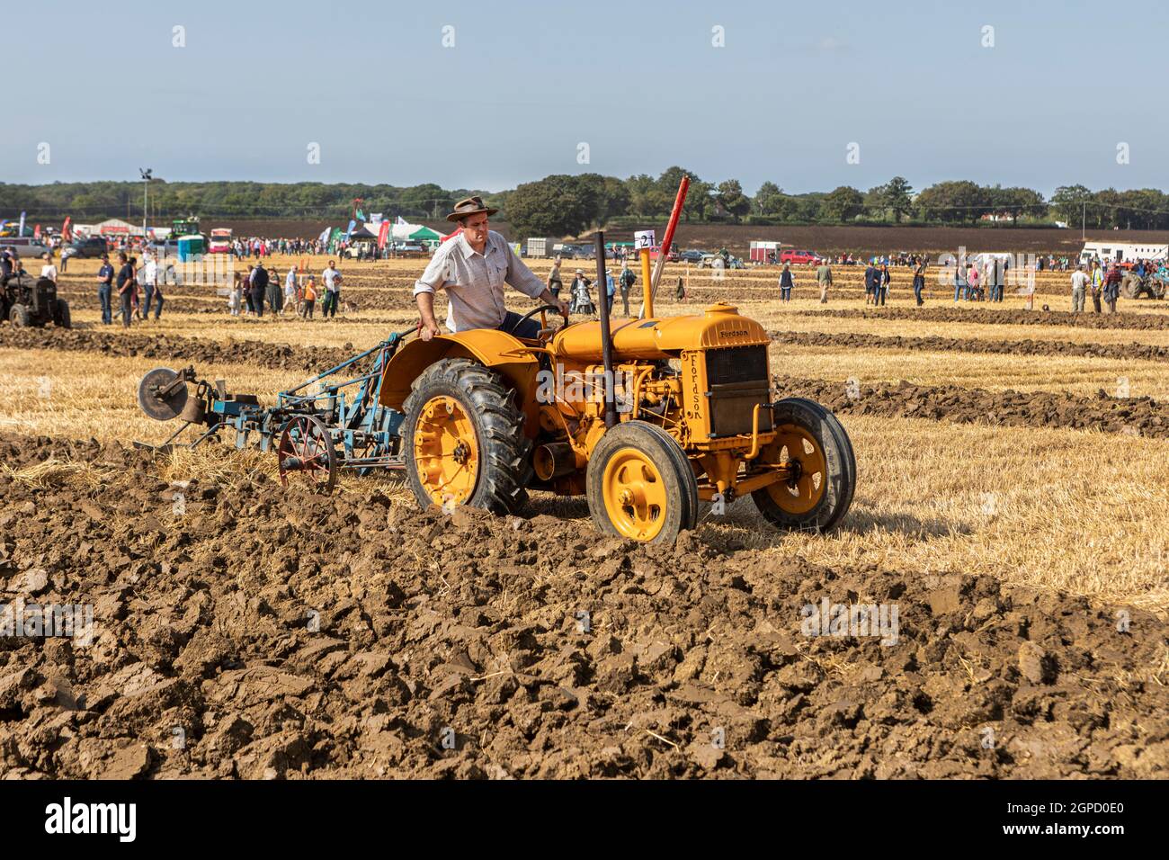 A classic old yellow Fordson tractor ploughing at a competition Stock