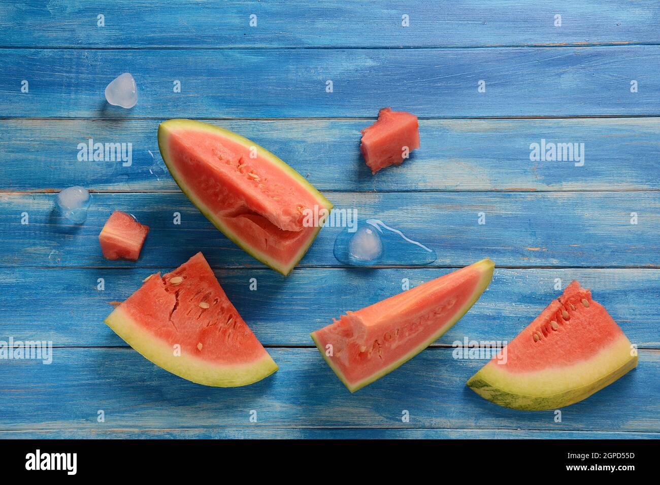 Fresh watermelon slices with ice cubes on a blue wooden rustic ...