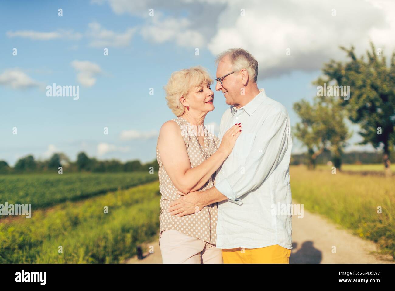 Senior couple embracing each other in love outdoors under a blue sky with Stock Photo