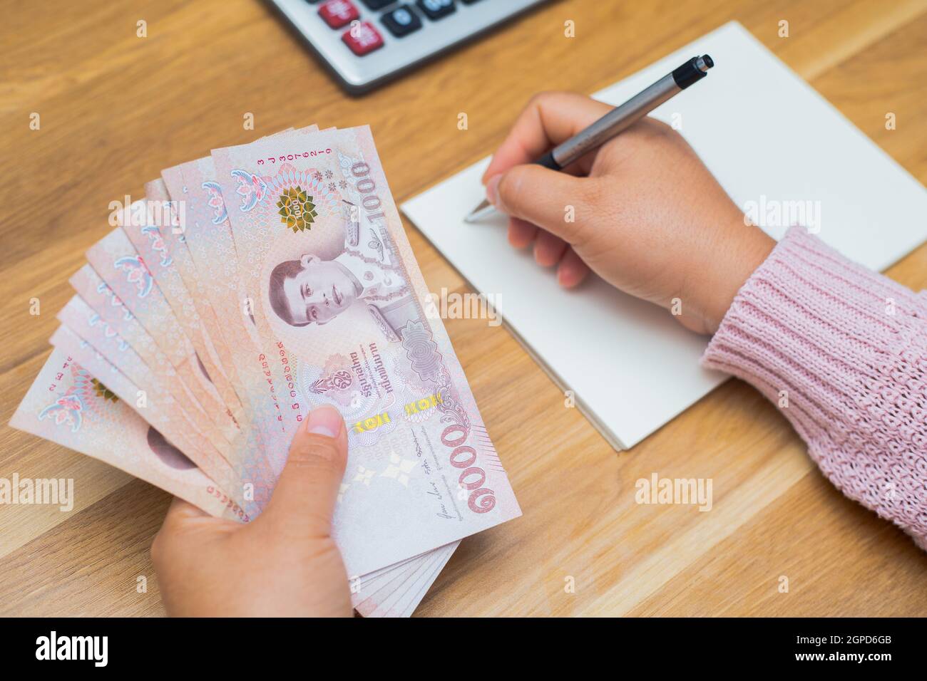 Close up of asian woman with calculator counting money.Woman calculate the spending at home. Stock Photo