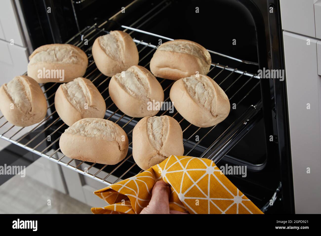 https://c8.alamy.com/comp/2GPD921/from-above-faceless-person-with-towel-removing-hot-glide-rack-with-fresh-bread-buns-out-of-oven-2GPD921.jpg