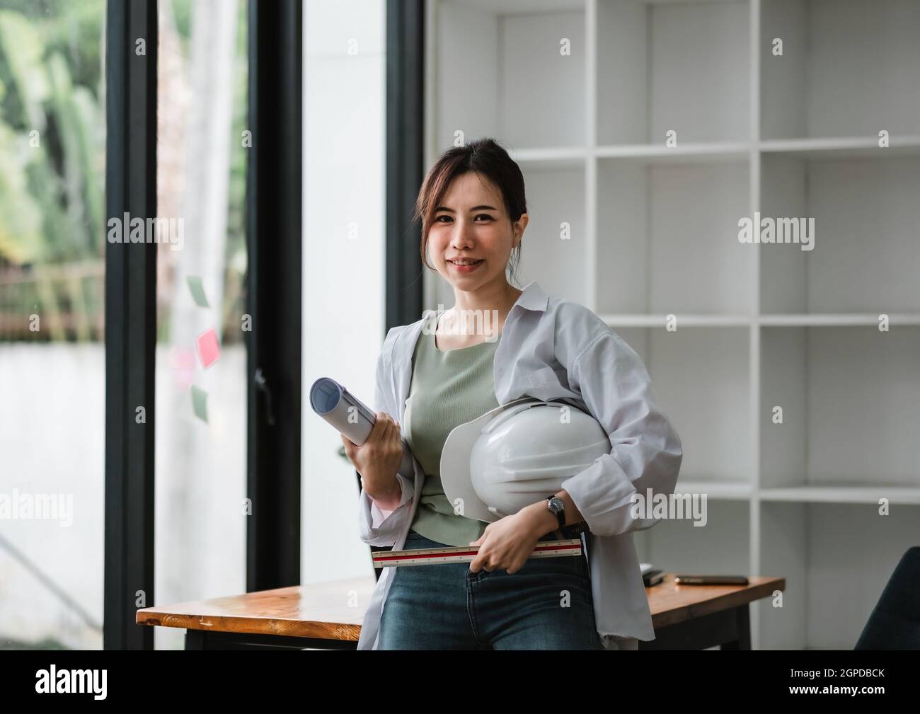 Portrait asian engineering woman standing with blueprint and safety helmet Stock Photo