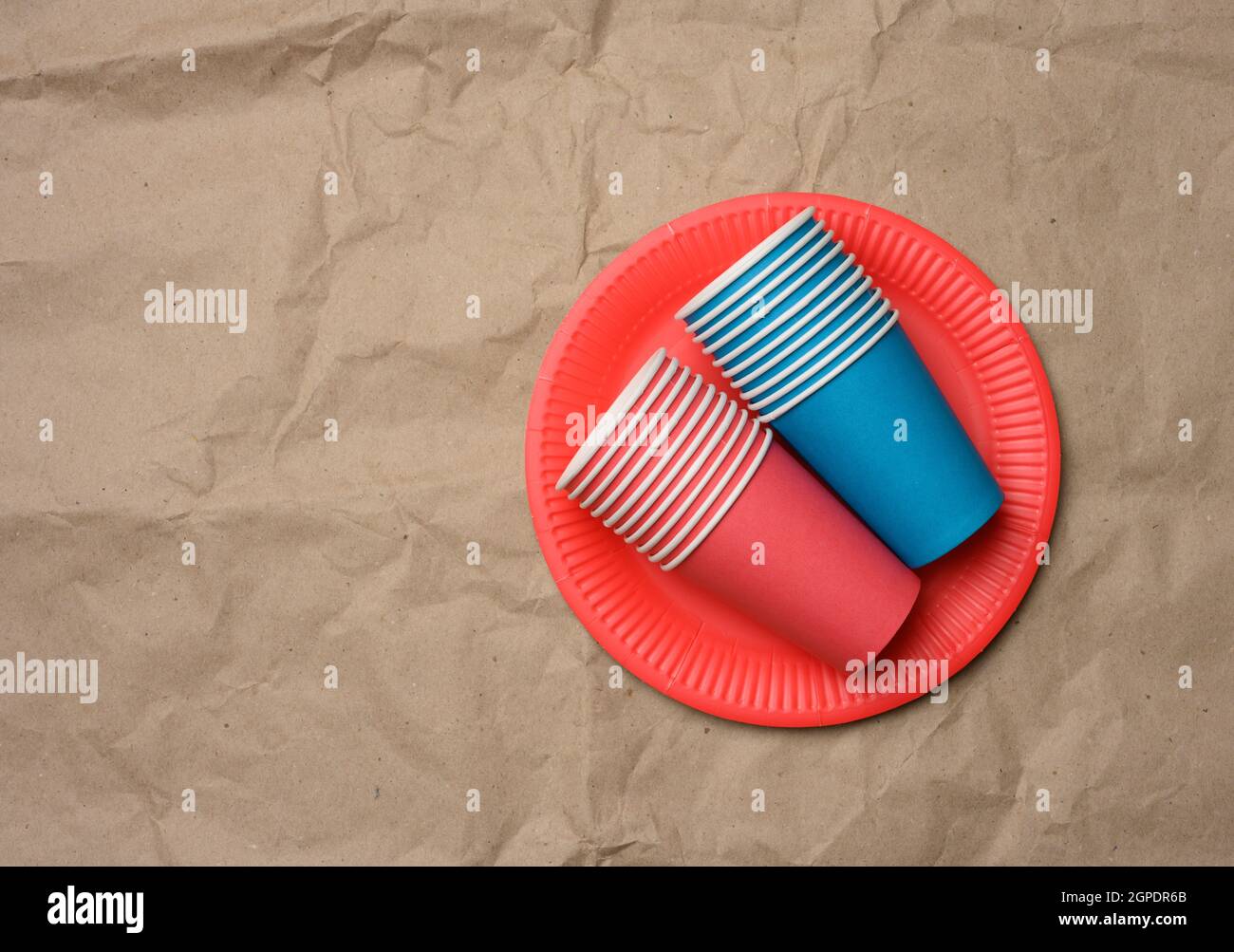 stack of paper cups and round plates on a brown paper background, top ...