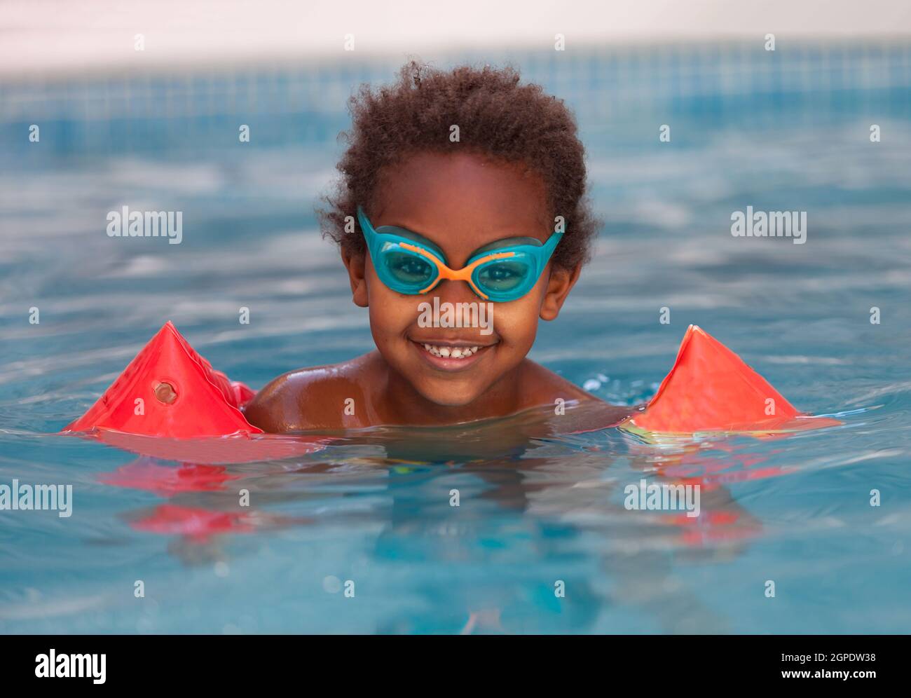 Little african child with orange sleeve floats in the pool Stock Photo