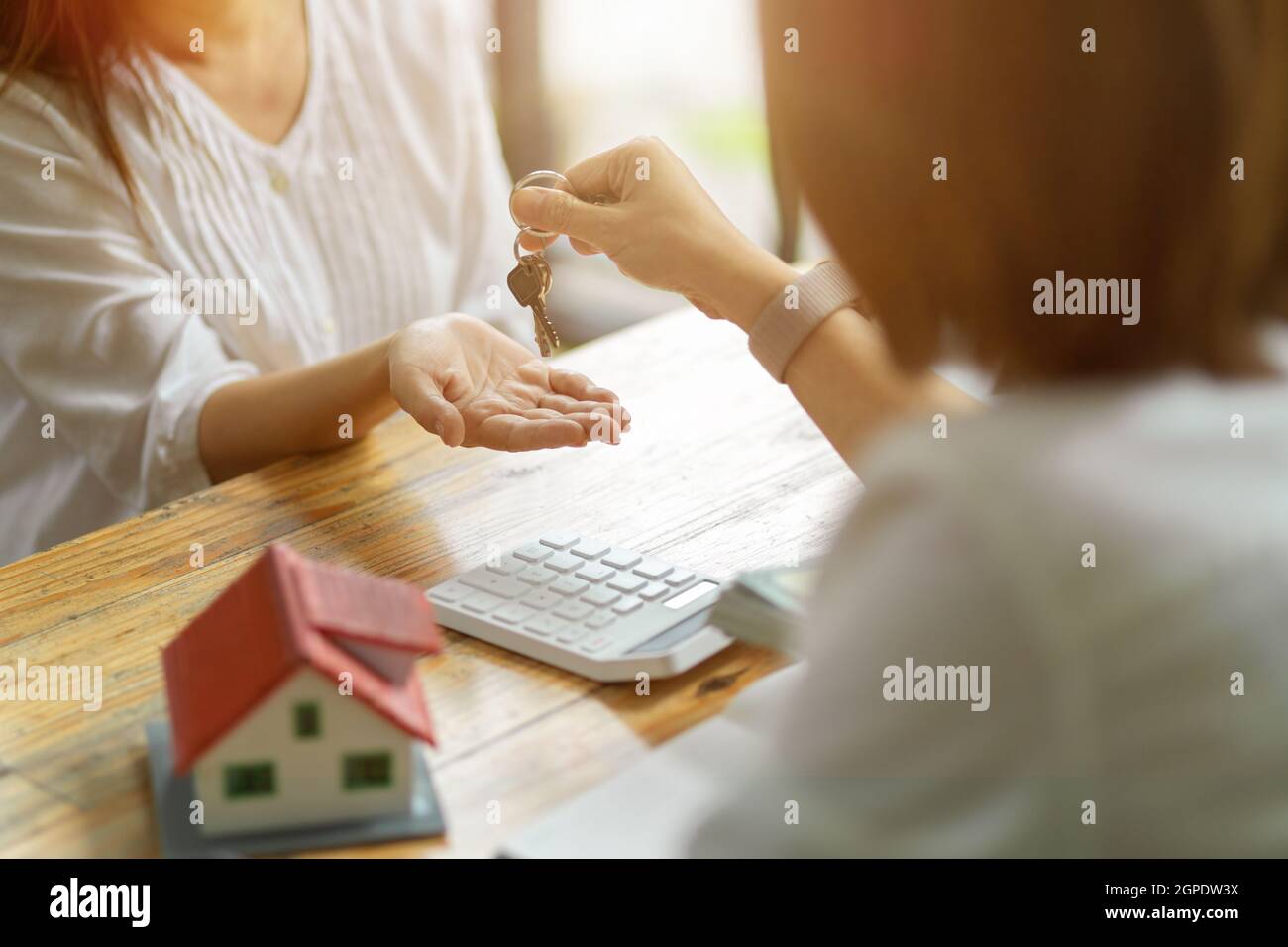 A new landlord receives a house keys chain from a real estate broker after paying a house deposit. Realtor and client, Real estate investment. Stock Photo