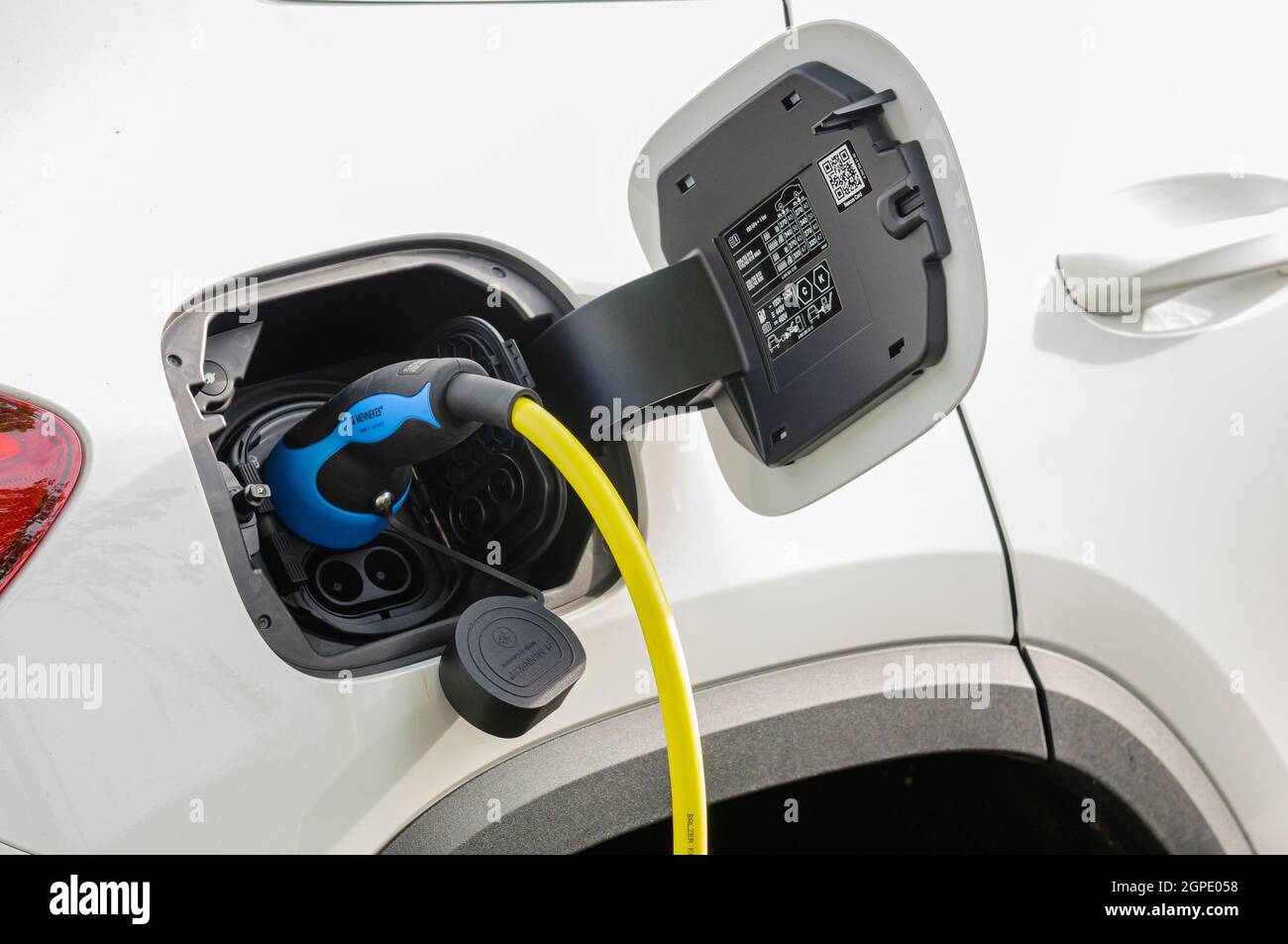 Cable plugged into a Mercedes EQ EQA electric vehicle at a car charging station Stock Photo