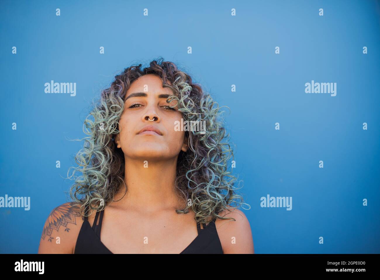 Woman with curly hair shot against blue background Stock Photo