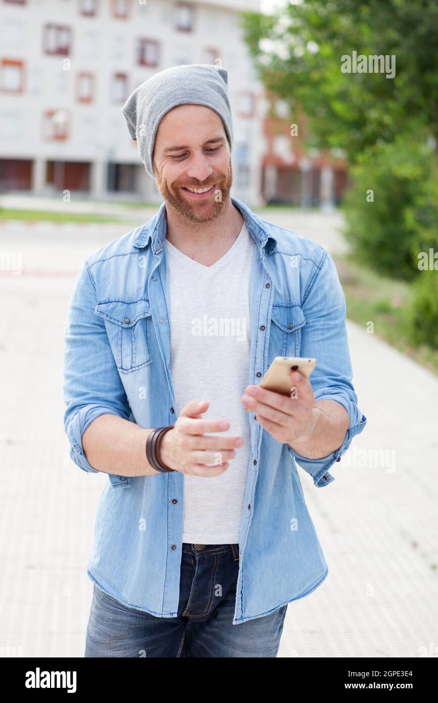 Casual fashion guy taking a walk with his mobile in the city Stock Photo