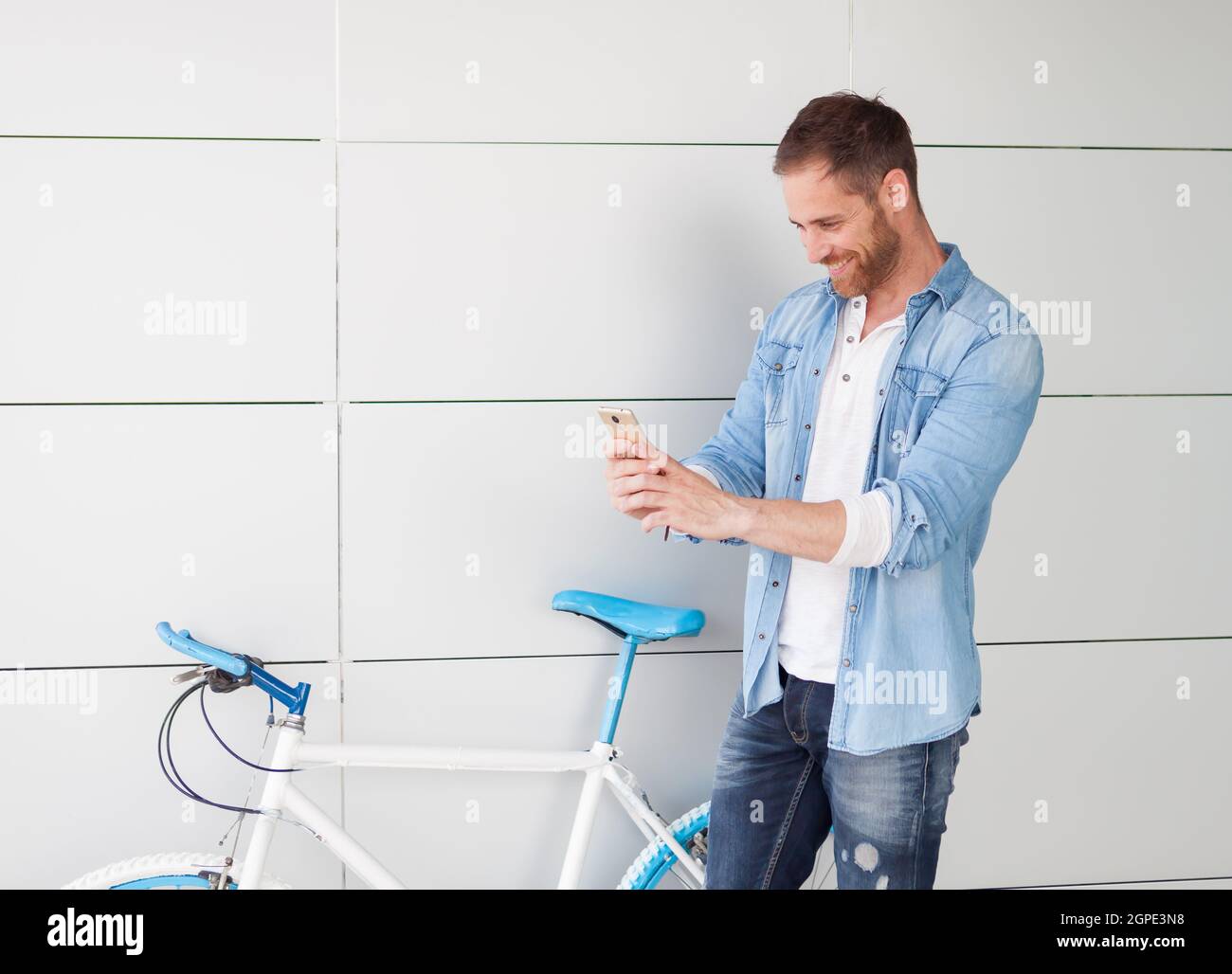 Casual guy next to a vintage bicycle with the mobile wearing denim shirt Stock Photo