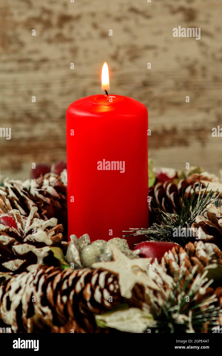 Red candle lit and pinecones for Christmas on a wooden background Stock Photo