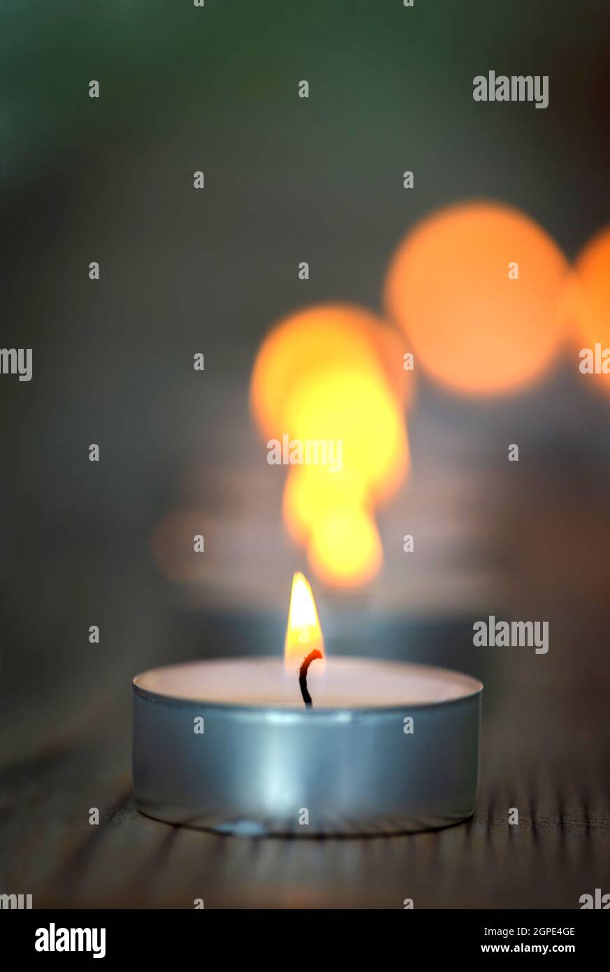 Many small burning candles on a wooden surface Stock Photo
